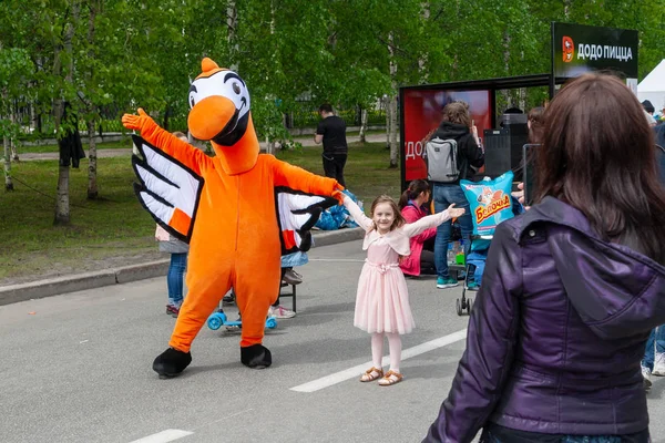 ドードーピッツェリアピザのシンボルであるオレンジ色の鳥の形をした大きな人形が、お祭りで子供たちと一緒に撮影されています。. — ストック写真