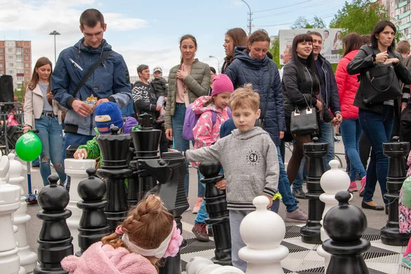 Des échecs géants. Enfants sur l'échiquier, parmi les pièces d'échecs géantes . — Photo