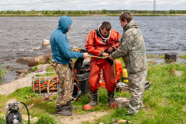 Twee assistenten helpen bij het voorbereiden van een professionele duiker voor werk. — Stockfoto