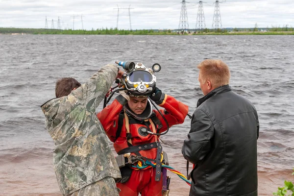 Два ассистента помогают водолазу надеть шлем. Глубоководные работы . — стоковое фото