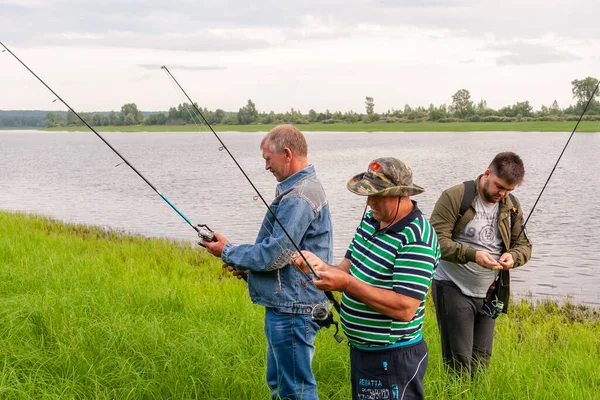 Tři rybáři na břehu jezera připravují rybářské náčiní — Stock fotografie