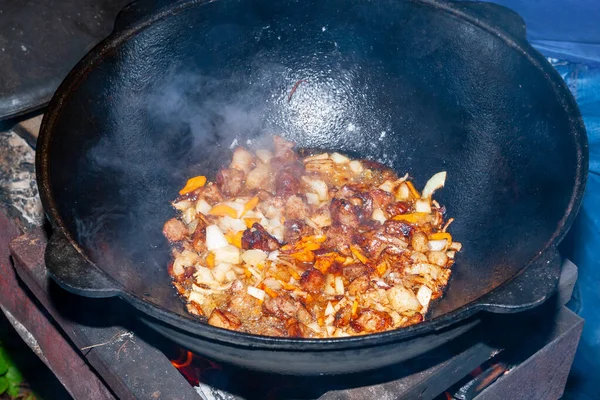 El proceso de cocinar pilaf asiático en el fuego. La carne se fríe en una c — Foto de Stock