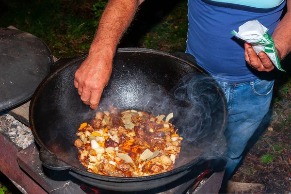 El proceso de cocinar pilaf asiático en el fuego. El hombre añade especias — Foto de Stock