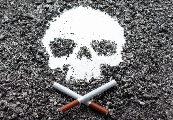 Zwei gekreuzte, knochenförmige Zigaretten liegen neben einem Schädel, der von — Stockfoto
