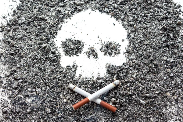 Dos cigarrillos huesudos cruzados yacen junto a un cráneo f — Foto de Stock