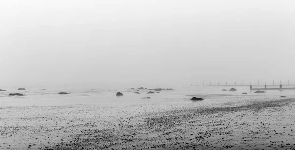 Monochrom Nebliger Strand Winter Mit Felsen Vordergrund Und Meeresbrüchen Dahinter — Stockfoto