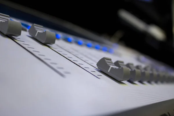 Low level view of a professional audio mixing console with soft focus background