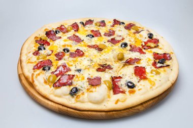 Beyaz arka planda pastırmalı, peynirli ve zeytinli yuvarlak pizza var.