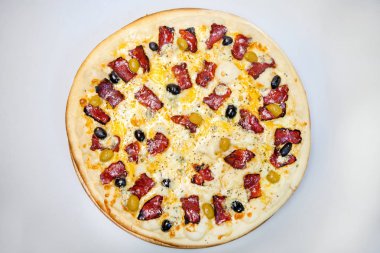 Pastırmalı, peynirli ve sebzeli pizza masanın üstünde.