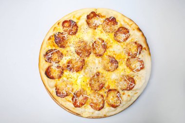 Sosisli, peynirli ve baharatlı yuvarlak pizza masanın ortasındaki ahşap bir tahtanın üzerinde.