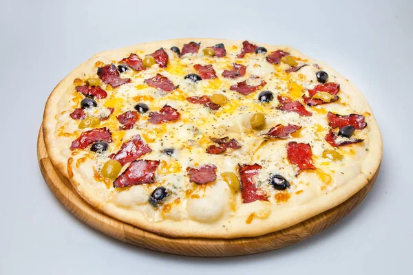 Beyaz arka planda pastırmalı, peynirli ve zeytinli yuvarlak pizza var.