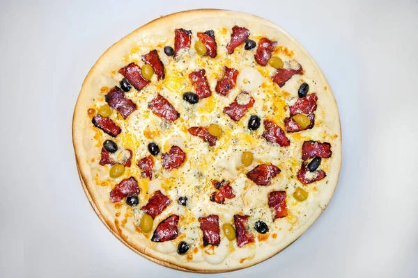 Pastırmalı, peynirli ve sebzeli pizza masanın üstünde.
