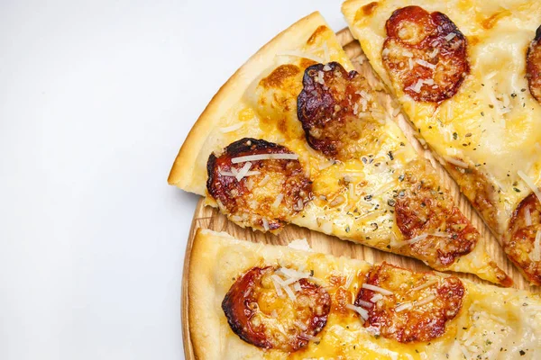 Peynirli, baharatlı ve sosisli hazır pizza parçaları pizzacıda bir tahtanın üzerinde duruyor.