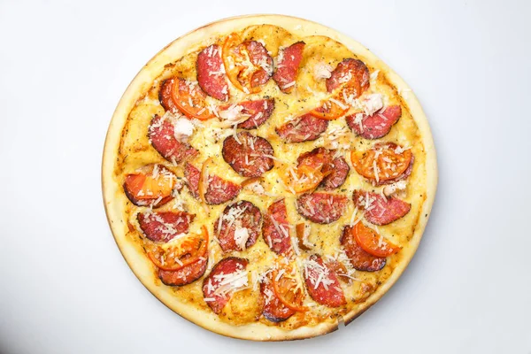 Domuz pastırması ve sosis dilimli ve peynirli yuvarlak pizza ahşap bir tahtanın üzerinde.