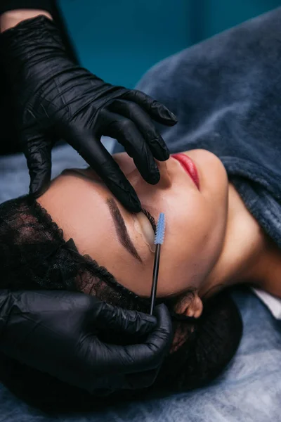 lamination of eyelashes in a beauty salon, master in black gloves