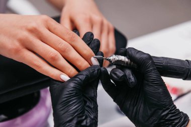 Manikürcü bir kıza çivi çakıyor.