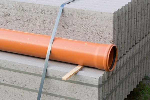Concrete blocks and plastic pvc sewage pipe on palette on building construction site
