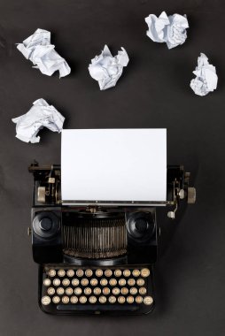Boş, boş bir kağıt yaprağına ve siyah arka plan üzerine ufalanmış Kağıt topları ile yukarıdan Vintage daktilo yukarıdan aşağıya flatlay vurdu