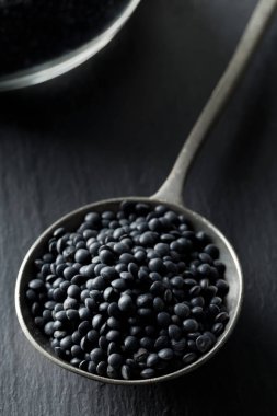Metal kaşık seçici odak siyah taş zemin üzerine siyah organik beluga mercimek yığını