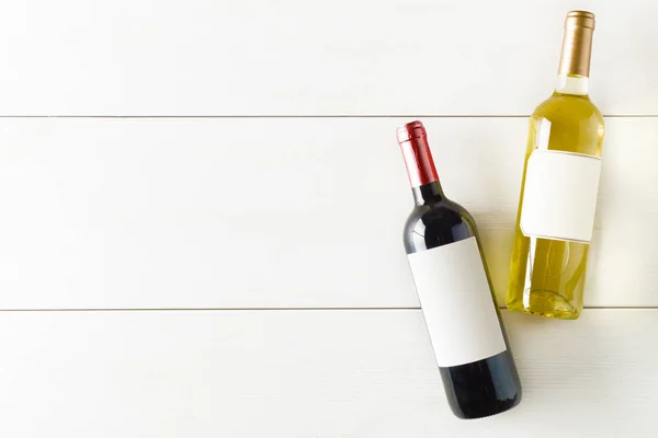 Red and white wine bottle on white wooden table flat lay from above with copy space