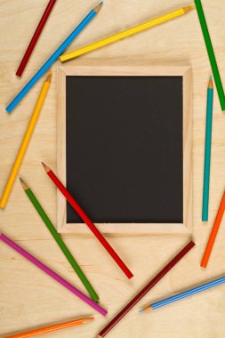 Siyah, kahverengi ahşap masa düz renkli kalemler ile boş, boş kara tahta yukarıdan kopya alanı ile yatıyordu