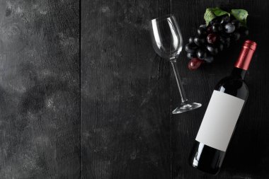 Kopya alanı ile yukarıdan kırmızı şarap şişesi bardak şarap ve üzüm koyu ahşap masa düz üzerinde yatıyordu