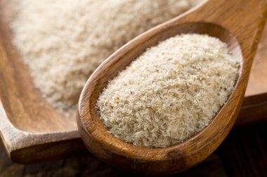 Tahta kaşık ve tablo ıslak zeminde psyllium kabuğu yığını. İsabgol olarak da bilinir psyllium kabuğu Hindistan'da bulunan dar ovata bitkisinin tohumlarından elde edilen lif olduğunu. Seçici odak.
