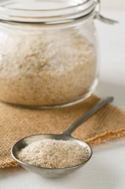 Psyllium kabuğu yığını isabgol beyaz masa arka plan üzerinde metal kaşık ve cam kavanoza da denir. İsabgol olarak da bilinir psyllium kabuğu Hindistan'da bulunan dar ovata bitkisinin tohumlarından elde edilen lif olduğunu. Seçici odak.