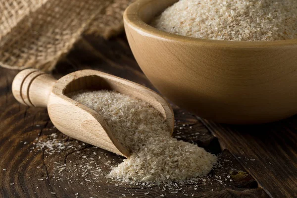 Psyllium kabuğu ahşap kepçe ve tablo ıslak zeminde yığını. İsabgol olarak da bilinir psyllium kabuğu Hindistan'da bulunan dar ovata bitkisinin tohumlarından elde edilen lif olduğunu. Seçici odak.