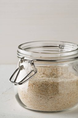 Psyllium kabuğu yığını isabgol cam beyaz masa arka plan üzerinde de denir. İsabgol olarak da bilinir psyllium kabuğu Hindistan'da bulunan dar ovata bitkisinin tohumlarından elde edilen lif olduğunu. Seçici odak.