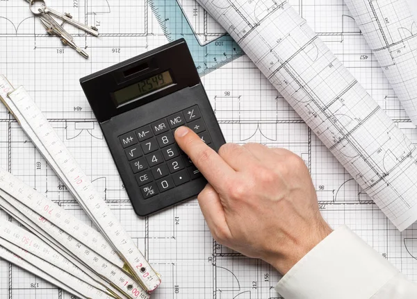 Architect met behulp van de calculator op architectonische blauwdruk huis buil — Stockfoto