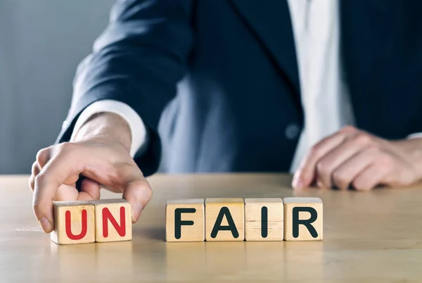 Business man puts away first two letters from the word unfair