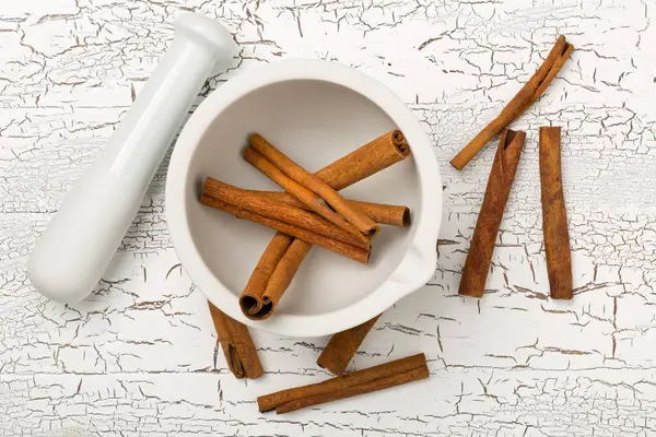 Tied dried cinnamon sticks in white mortar on rustic white woode — Stock Photo, Image
