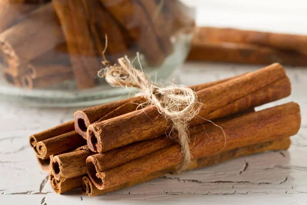 Tied dried cinnamon sticks on rustic white wooden table - select — Stock Photo, Image