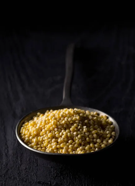 Pilha de painço dourado, uma semente de grão sem glúten, em colher de metal — Fotografia de Stock