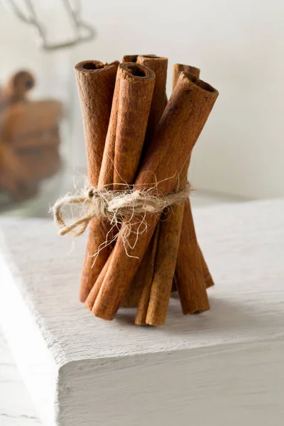 Tied dried cinnamon sticks on white board on table - selective f — Stock Photo, Image