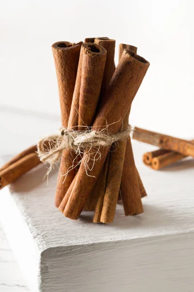 Tied dried cinnamon sticks on white board on table - selective f — Stock Photo, Image