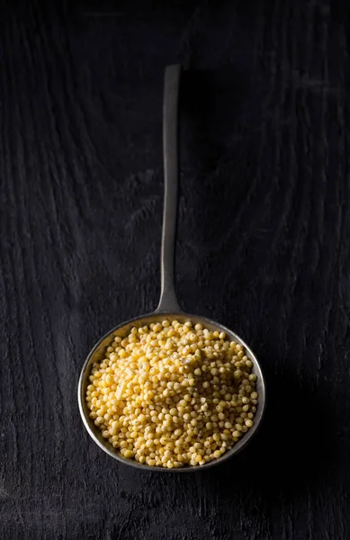 Stos złotą proso, glutenu ziarno ziarna, w metalowej łyżce — Zdjęcie stockowe