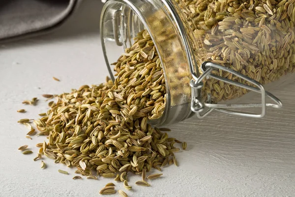 Dried fennel seeds in glass storage jar on white wooden table — Stock Photo, Image