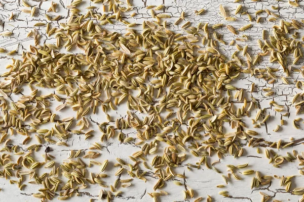 Сушеные семена фенхеля разбросаны по деревенскому белому деревянному столу — стоковое фото