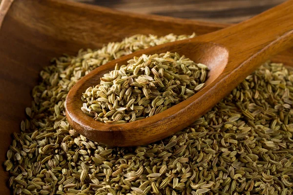 Dried fennel seeds in wooden bowl with wooden spoon on rustic wo — Stock Photo, Image