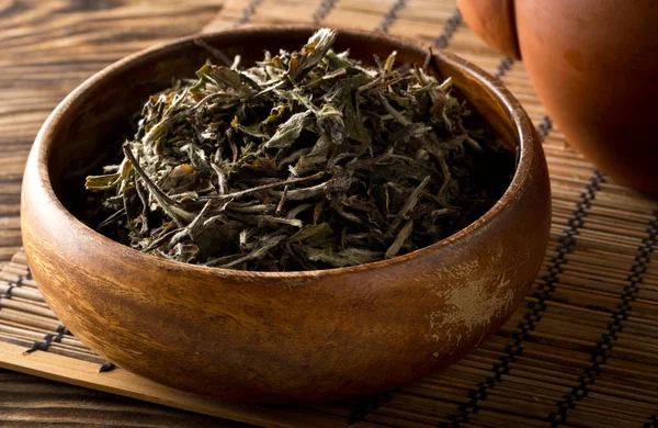 Сухе, сире біле листя чаю в дерев'яній мисці на бамбуковому килимку backgro — стокове фото