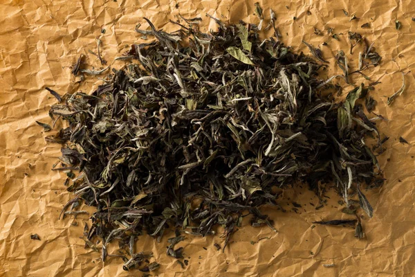 Dried, raw white tea leaves on brown packing paper background to