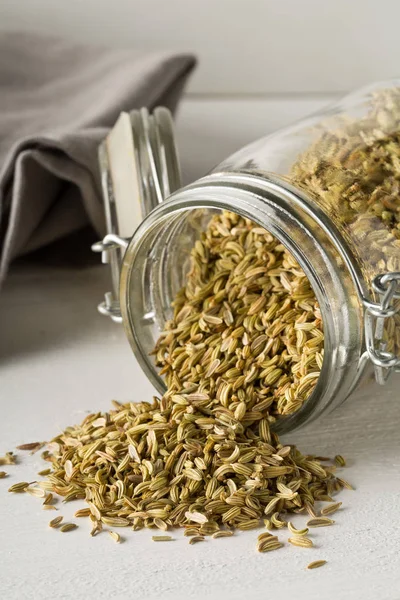 Dried fennel seeds in glass storage jar on white wooden table — Stock Photo, Image