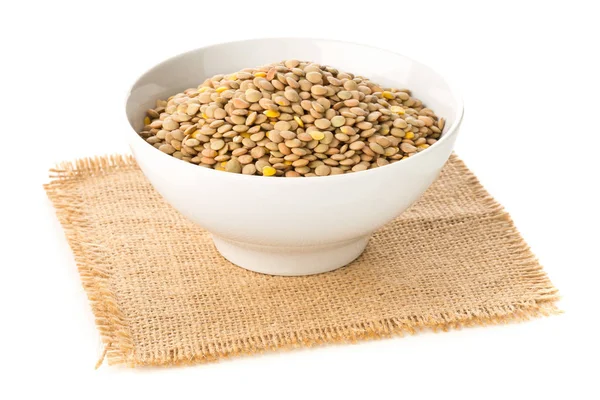 生,干,未煮熟的棕色扁豆豆类在粗麻布的白色碗 — 图库照片