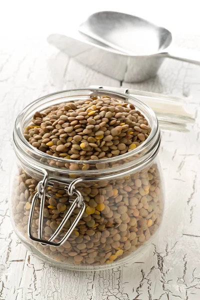 Leguminosas de lentilha marrom cruas, secas e não cozidas em frasco de armazenamento de vidro em — Fotografia de Stock