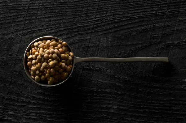 Leguminosas de lentilhas marrons cruas, secas e não cozidas em colher de metal em madeira t — Fotografia de Stock