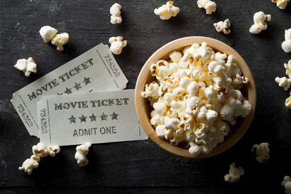 Movie tickets and bowl of popcorn on dark background. Home theat