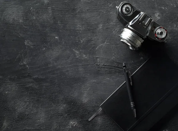 Caméra à film analogique rétro avec cahier et stylo sur table en bois sombre — Photo