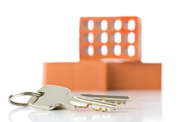 House keys in front of bricks over white background - home owner — Stock Photo, Image